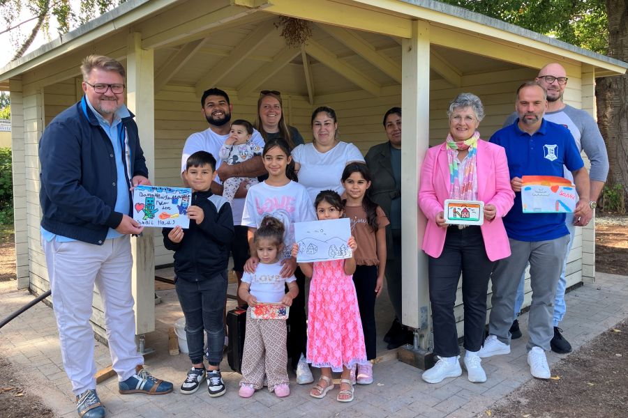 Das Foto zeigt eine Gruppe von Menschen, einige halten von Kindern gemalte Bilder in den Händen.