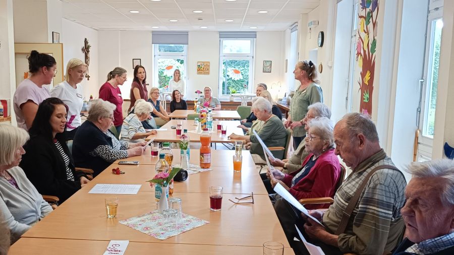 Das Foto zeigt Menschen um einen Tisch mit Liedzetteln. Sie singen gemeinsam. Zum Grillfest gehörte auch das gemeinsame Singen. | Foto: Caritas