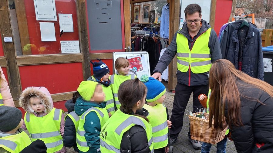 Das Foto zeigt eine Gruppe Kinder mit ihrem Betreuer vor dem Caritex-Laden Northeim.