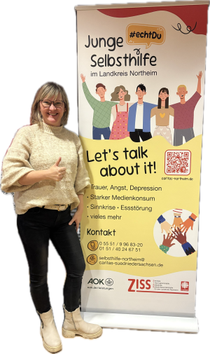 Das Bild zeigt Anna Holland vor dem Roll-Up der Jungen Selbsthilfe.