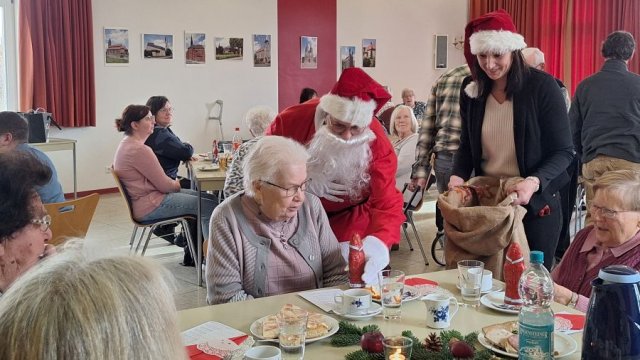 Das Foto zeigt, wie eine als Nikolaus verkleidete Person Geschenke verteilt.